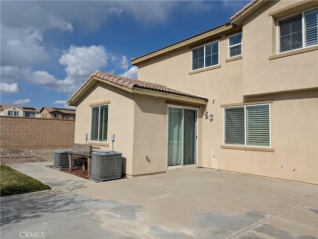 rear view of house featuring a tile roof, stucco siding, fence, central air condition unit, and a patio
