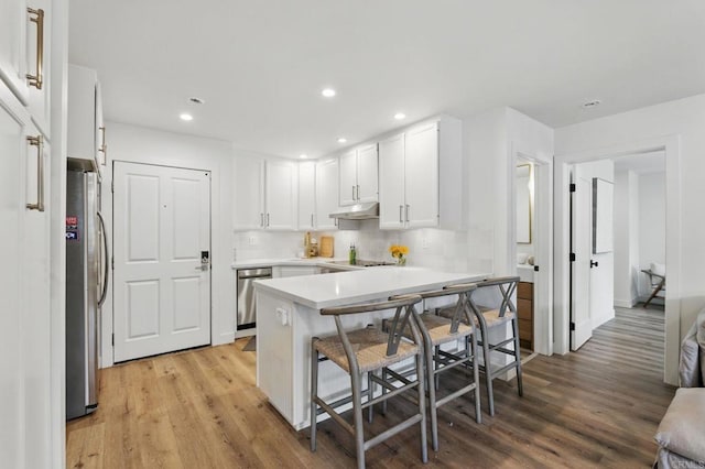 1562 Camino Del Mar Unit 639, Del Mar, CA 92014 - kitchen featuring appliances with stainless steel finishes, light wood-style flooring, white cabinetry, a kitchen bar, and light countertops