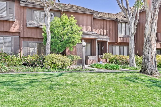 view of front of property with a shingled roof and a front yard