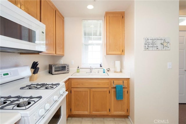 kitchen with a toaster, white appliances, light countertops, and a sink