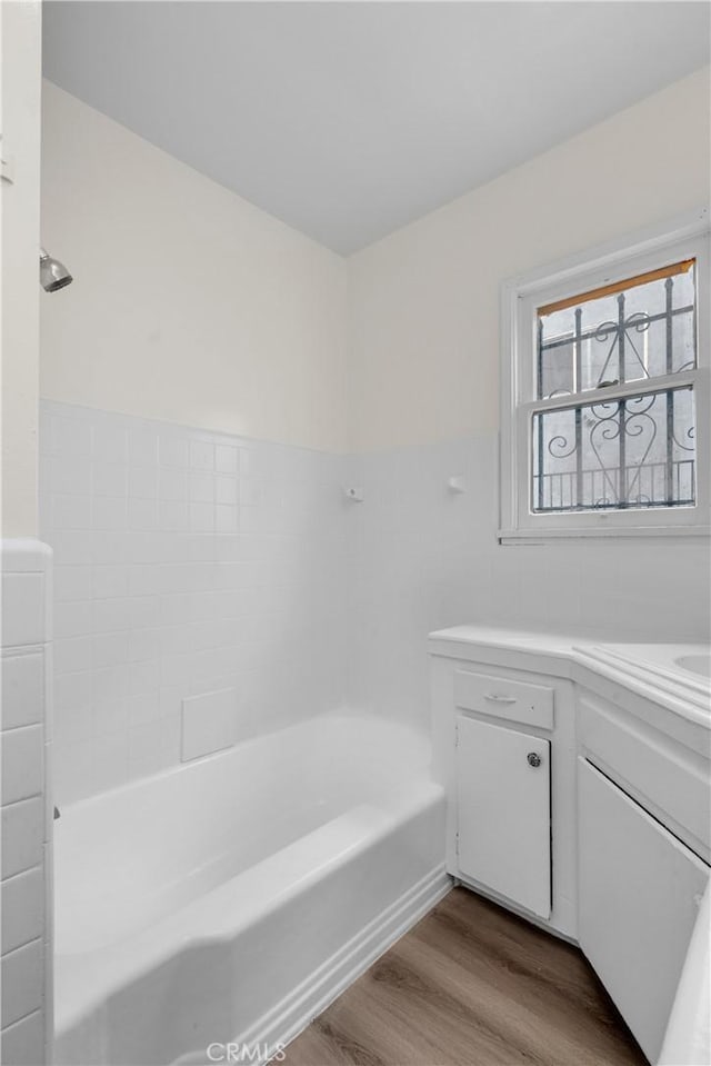 full bathroom with a shower, wood finished floors, vanity, and a washtub