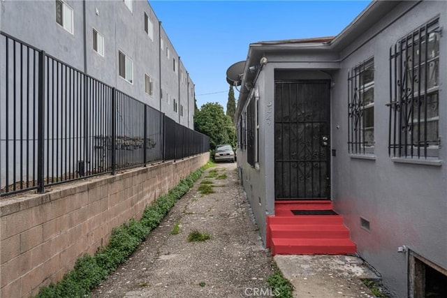 doorway to property with stucco siding and fence