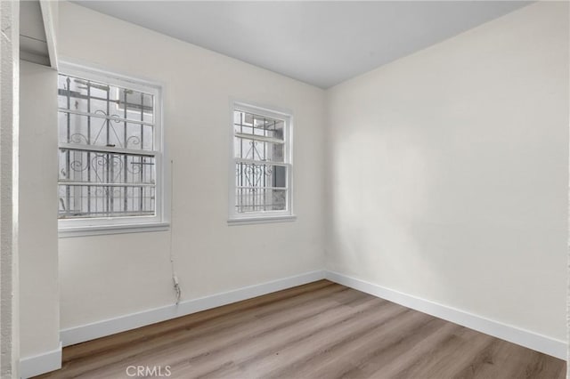 spare room featuring baseboards and wood finished floors