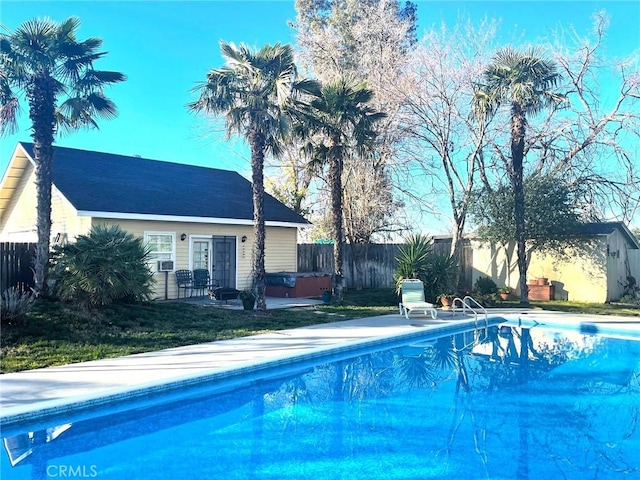view of swimming pool with a jacuzzi, a fenced backyard, an outbuilding, a fenced in pool, and a patio area