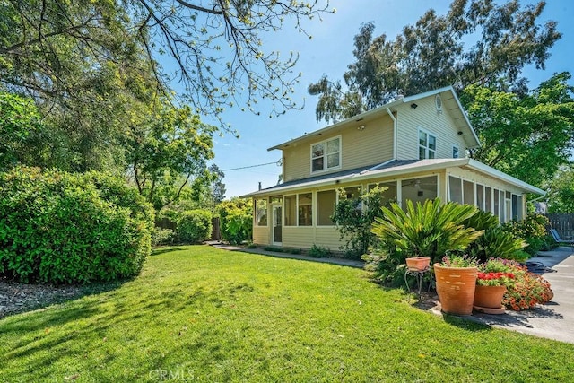 rear view of property featuring fence, a sunroom, and a lawn