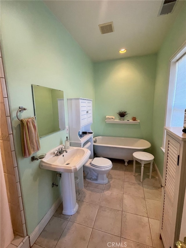 full bath featuring tile patterned flooring, visible vents, a freestanding bath, and baseboards