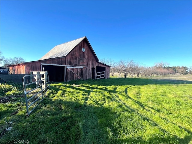 view of barn featuring a lawn and fence