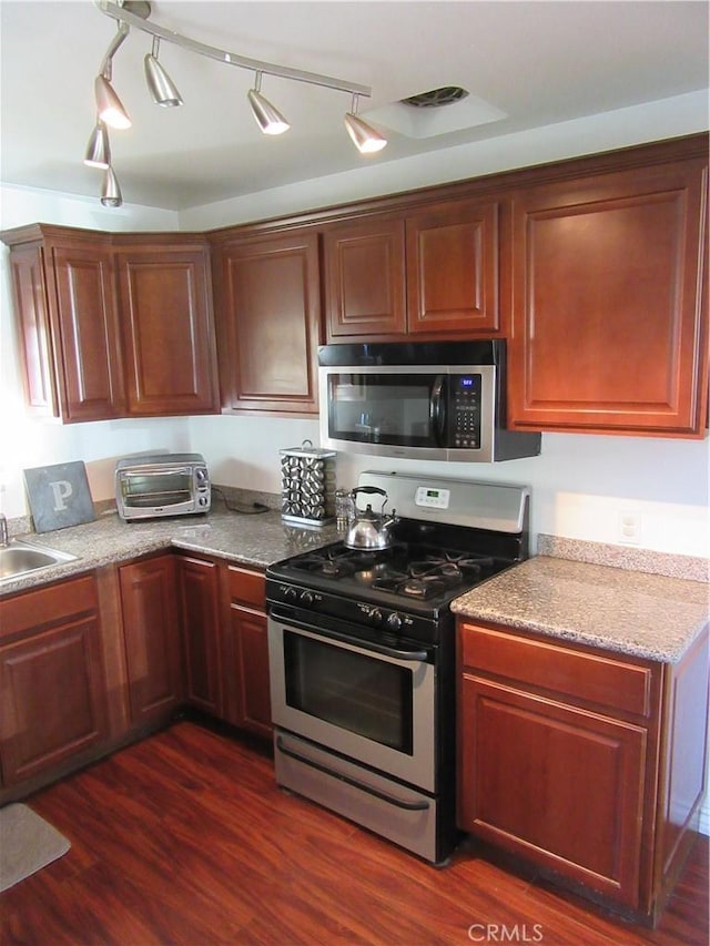 kitchen with appliances with stainless steel finishes, a toaster, a sink, and dark wood-style floors