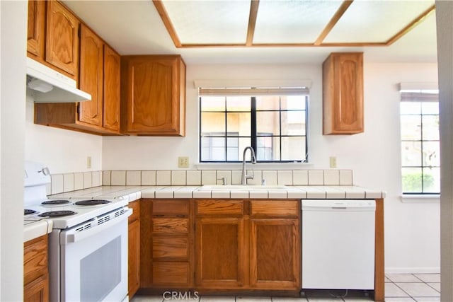 kitchen with plenty of natural light, white appliances, a sink, and brown cabinets