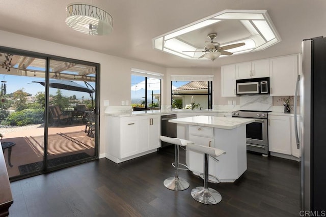 13336 Corte De Comares, San Diego, CA 92128 - kitchen with stainless steel appliances, dark wood-type flooring, ceiling fan, a kitchen island, and decorative backsplash