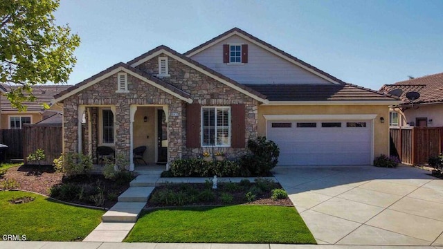 view of front of home with an attached garage, fence, driveway, and a front lawn