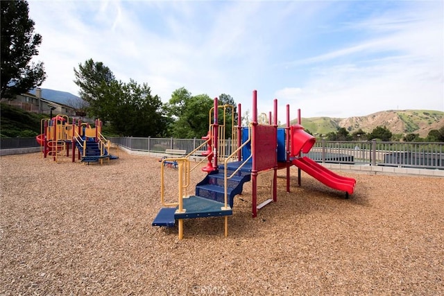 communal playground featuring fence and a mountain view