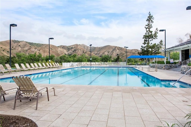 pool featuring a mountain view, a patio area, and fence