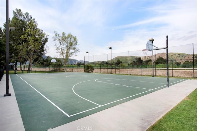 view of sport court featuring a mountain view, fence, and community basketball court