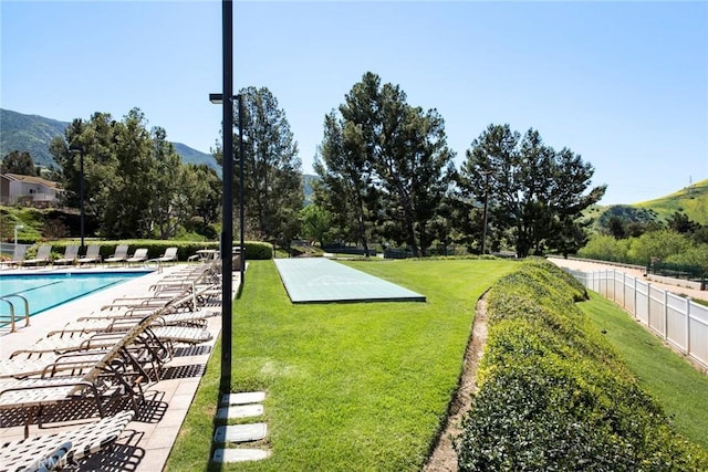 view of yard with a mountain view, fence, a community pool, and a patio area