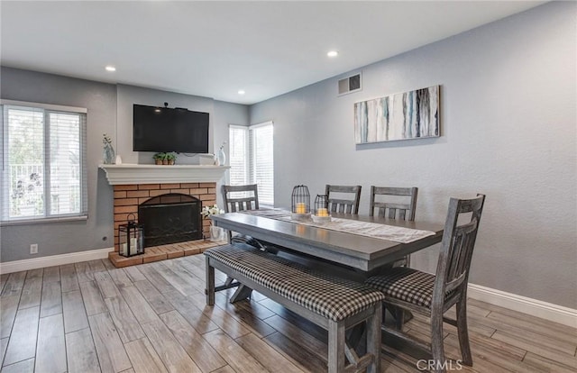 dining space with recessed lighting, wood finished floors, a fireplace, baseboards, and visible vents