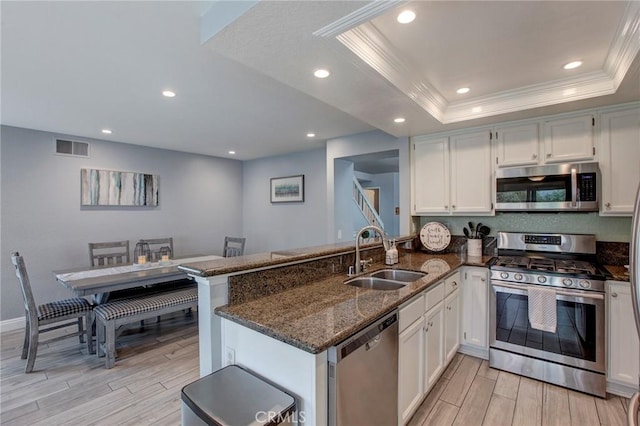 kitchen with appliances with stainless steel finishes, visible vents, light wood-style flooring, and a sink