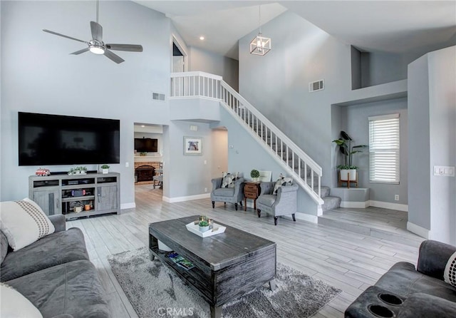 living room featuring visible vents, wood finished floors, stairway, and a towering ceiling