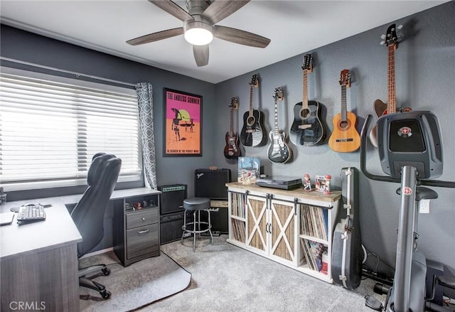 carpeted home office with a ceiling fan and a textured wall