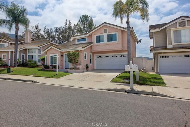 traditional home with stucco siding, fence, a garage, a front yard, and concrete driveway
