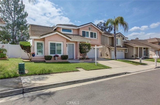 view of front of property featuring a tile roof, an attached garage, driveway, stucco siding, and fence