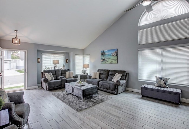 living area featuring baseboards, high vaulted ceiling, wood finished floors, and ceiling fan
