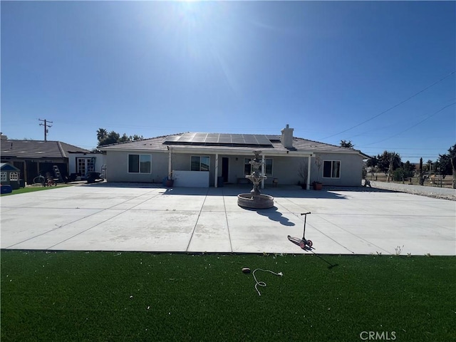 17238 Danbury Ave, Hesperia, CA 92345 - rear view of house featuring roof mounted solar panels, a lawn, stucco siding, and a patio area