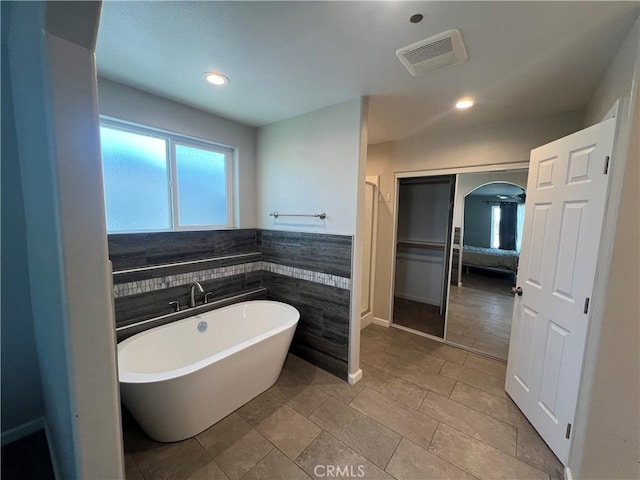 17238 Danbury Ave, Hesperia, CA 92345 - bathroom with tile walls, a soaking tub, wainscoting, visible vents, and recessed lighting