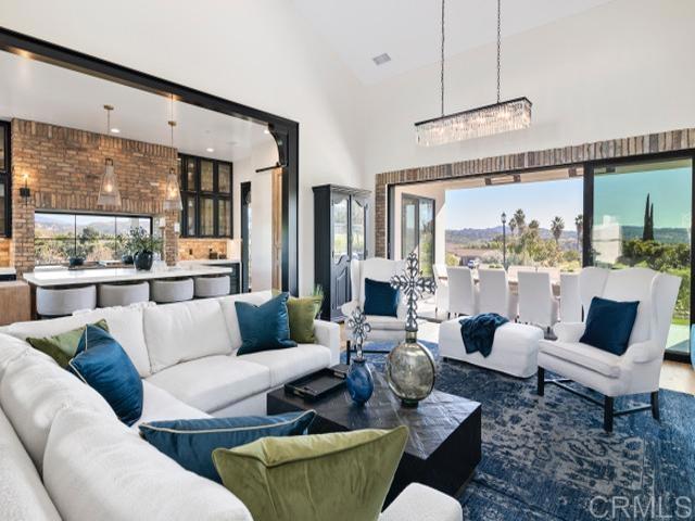 2255 Via Dulcea, Fallbrook, CA 92028 - living room with high vaulted ceiling, a chandelier, and brick wall