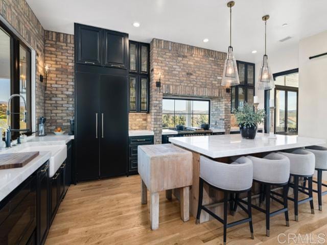 2255 Via Dulcea, Fallbrook, CA 92028 - kitchen featuring healthy amount of natural light, light countertops, brick wall, a breakfast bar, and glass insert cabinets