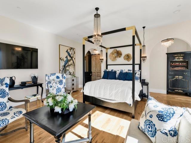 2255 Via Dulcea, Fallbrook, CA 92028 - bedroom with arched walkways, a chandelier, and wood finished floors