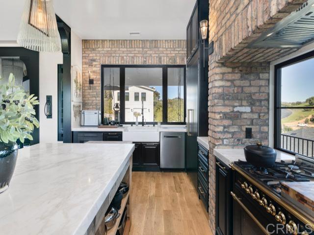2255 Via Dulcea, Fallbrook, CA 92028 - kitchen with gas stove, plenty of natural light, light wood-style floors, brick wall, and dark cabinetry