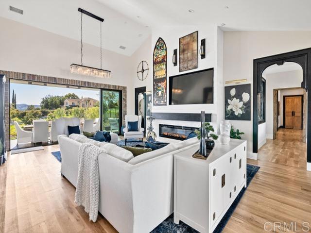 2255 Via Dulcea, Fallbrook, CA 92028 - living area with light wood-style floors, high vaulted ceiling, and a glass covered fireplace