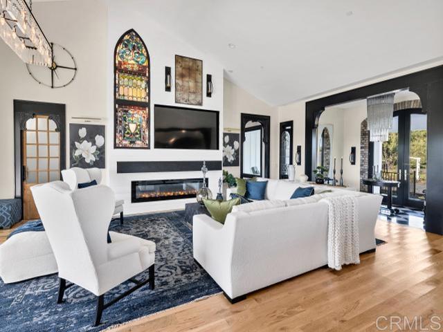 2255 Via Dulcea, Fallbrook, CA 92028 - living room with wood finished floors, french doors, high vaulted ceiling, a glass covered fireplace, and arched walkways