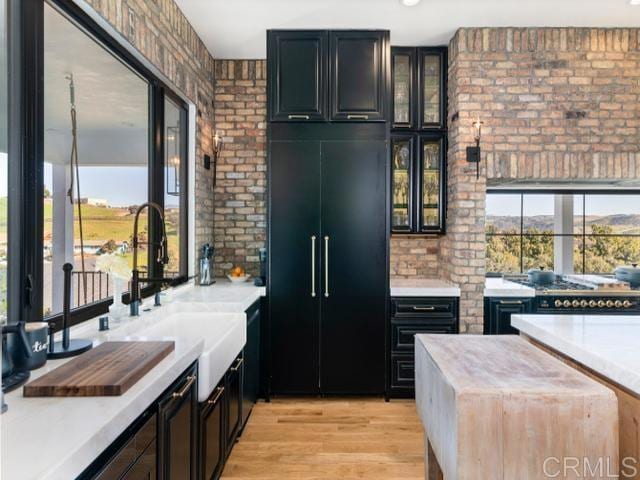 2255 Via Dulcea, Fallbrook, CA 92028 - kitchen featuring light countertops, brick wall, paneled built in fridge, and glass insert cabinets