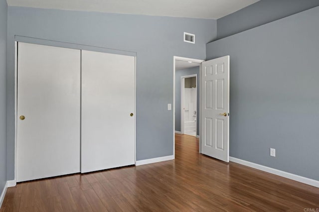 unfurnished bedroom featuring visible vents, baseboards, vaulted ceiling, and wood finished floors