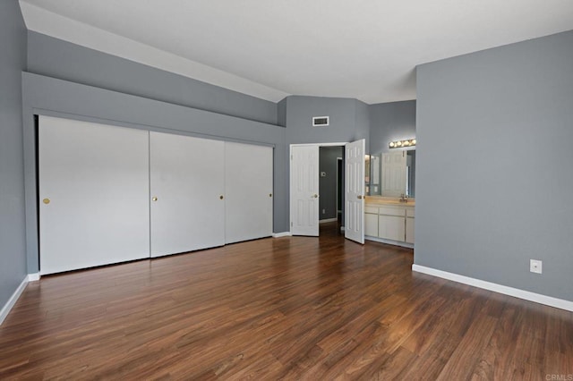 unfurnished bedroom with a closet, baseboards, dark wood-type flooring, visible vents, and a sink
