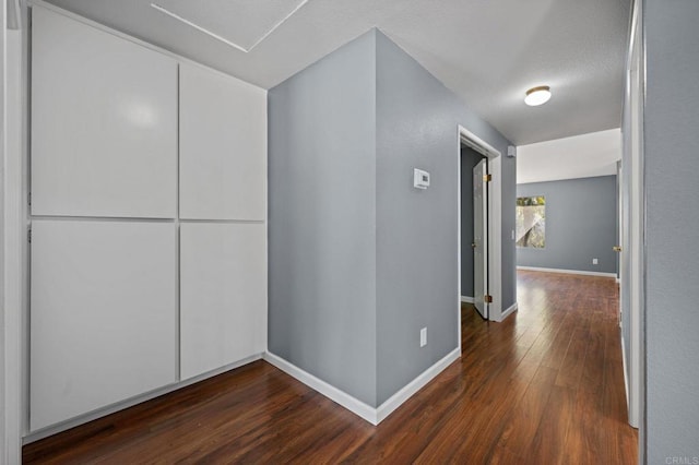 hall featuring dark wood-style flooring and baseboards
