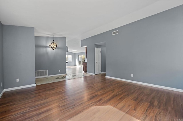 unfurnished living room with wood finished floors, baseboards, and visible vents