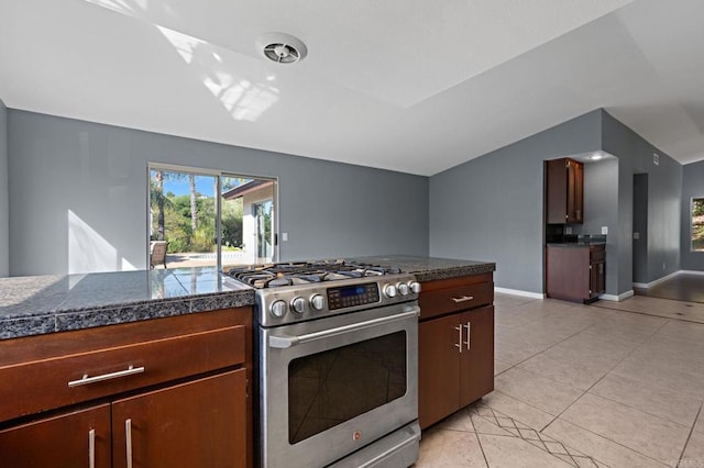 kitchen with light tile patterned floors, baseboards, tile counters, stainless steel gas stove, and lofted ceiling