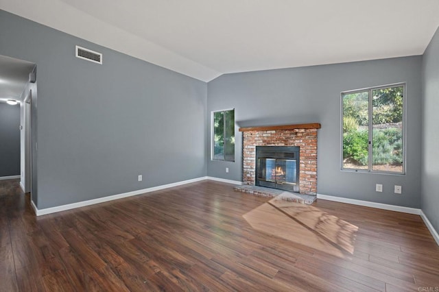 unfurnished living room featuring a fireplace, vaulted ceiling, visible vents, wood finished floors, and baseboards