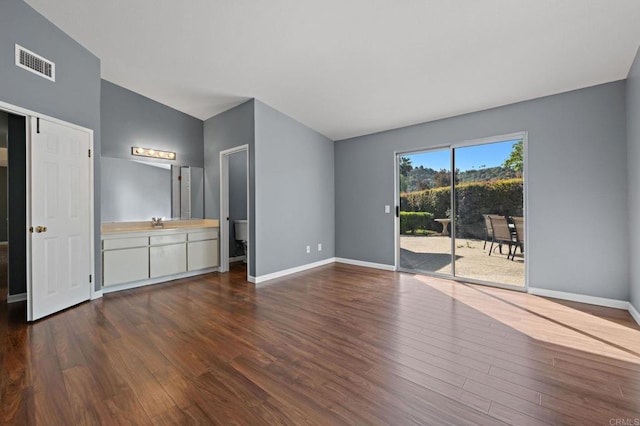 unfurnished living room with baseboards, dark wood-style floors, visible vents, and vaulted ceiling