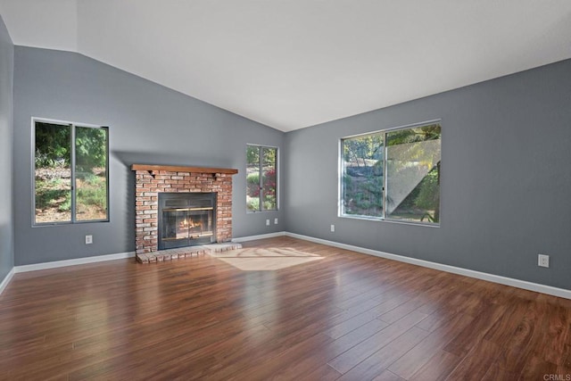 unfurnished living room with a fireplace, baseboards, wood finished floors, and lofted ceiling