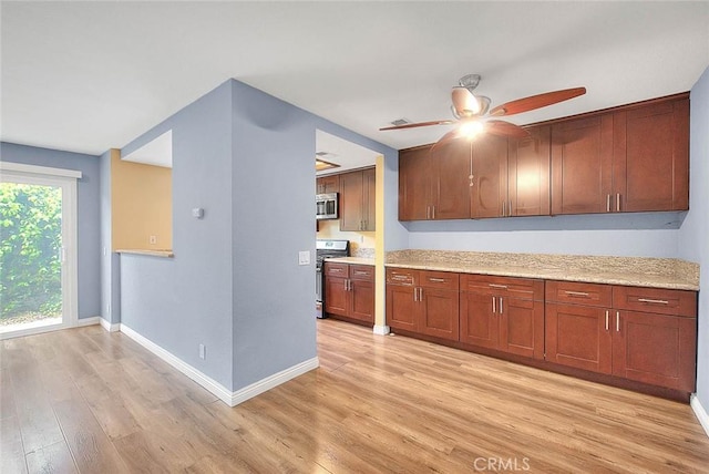 kitchen with appliances with stainless steel finishes, ceiling fan, light wood finished floors, baseboards, and brown cabinetry