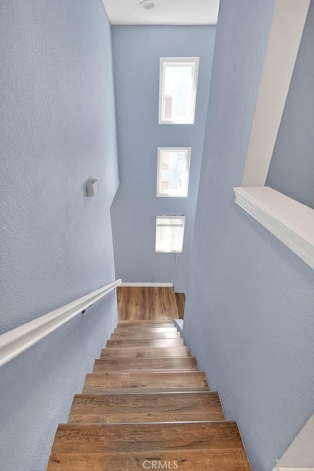 stairs with a textured wall and wood finished floors