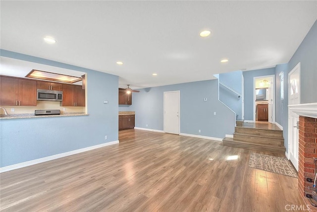 unfurnished living room featuring light wood-style floors, stairway, recessed lighting, a ceiling fan, and baseboards