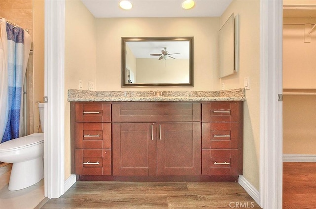 bathroom with a ceiling fan, baseboards, toilet, vanity, and wood finished floors