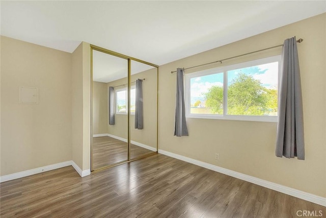 unfurnished bedroom featuring baseboards, a closet, and wood finished floors