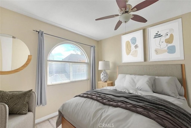 bedroom with light wood-style floors, baseboards, and ceiling fan