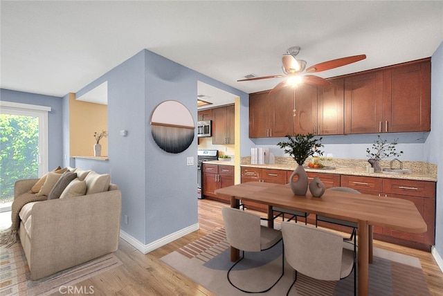 dining space featuring light wood-style floors, a ceiling fan, and baseboards